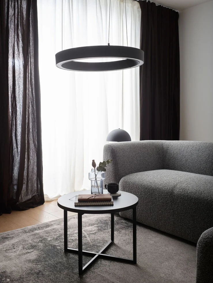 Neutralna barwa światła w salonie, szara sofa